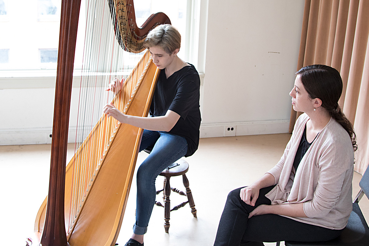 Photo of teacher, and student playing harp